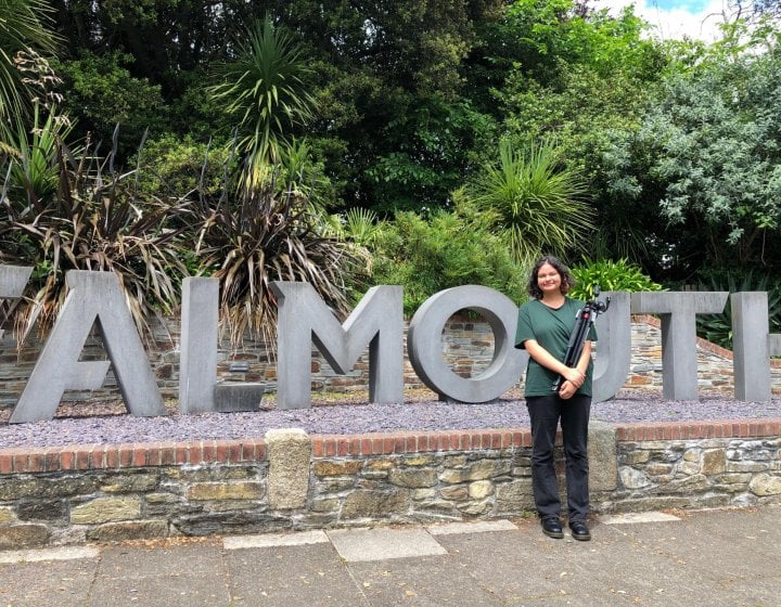 A woman stands in front of the Falmouth sign on Woodlane